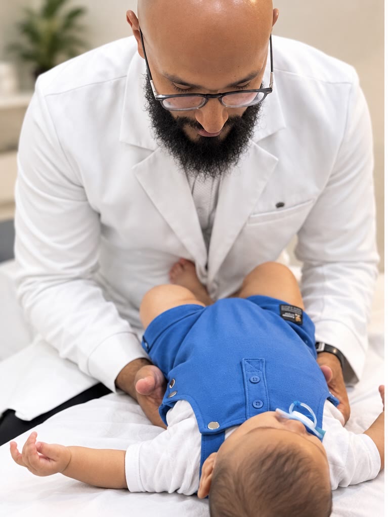 Dr. Hidelvani realizando técnica suave na região abdominal e do quadril de um bebê deitado
